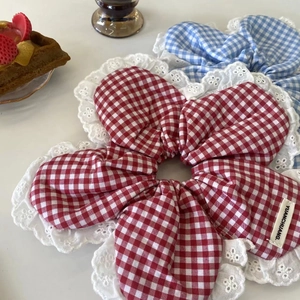 Close-up of plaid fabric scrunchies with white lace edges on a white table