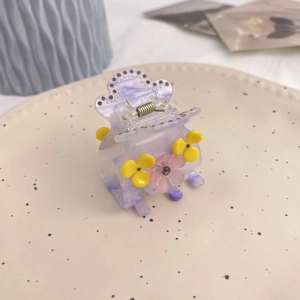 Pince à cheveux marguerite violette avec strass sur un plateau en céramique blanc