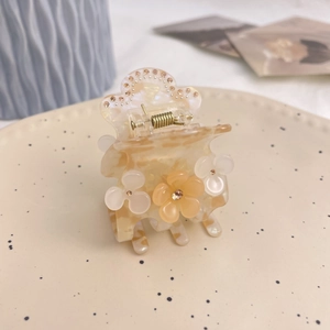 Détail d'une pince à cheveux marguerite avec strass et finition texture marbrée