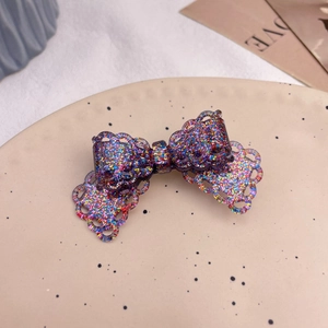 Detailed macro view of a lace-edged glitter bow hair clip with colorful resin sparkles