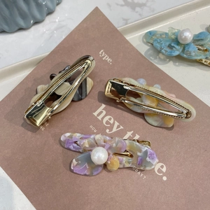 Detailed view of acetate butterfly hair clips with pearls and gold duckbill clips