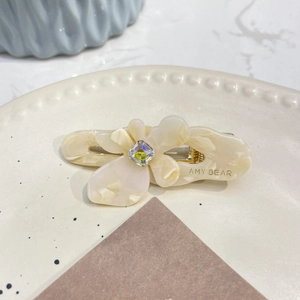 Dettaglio della clip per capelli a fiore in acetato crema con cristallo e clip dorata