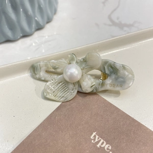 Detailed macro of vintage marble acetic hair clip with a large pearl on a ceramic tray