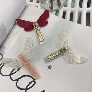 Detailed view of three butterfly hair clips in red, cream, and pink on a fashion magazine