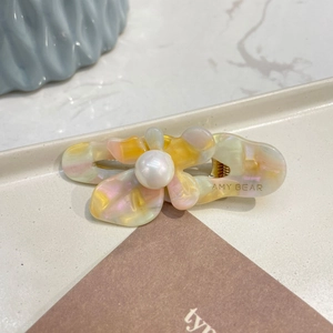 Pearlescent floral acetate hair clip with large pearl center on aesthetic display