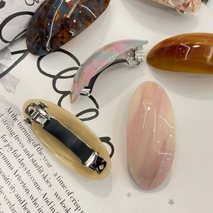 Detail view of oval acetate hair clips in multiple marble and tortoiseshell patterns