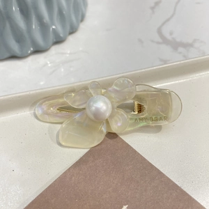 Detailed close-up of a floral acetate hair clip with a lustrous faux pearl center