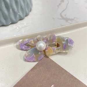 Detailed macro view of acetate floral hair clip with marble pattern and faux pearl center