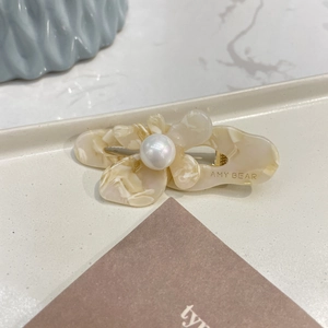 Detailed close-up of cream marble acetate flower hair clip with central iridescent pearl