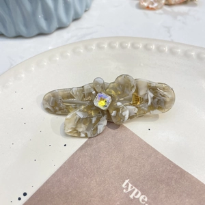 Dettaglio del fermaglio per capelli a fiore in acetato con trama marmorea e cristallo