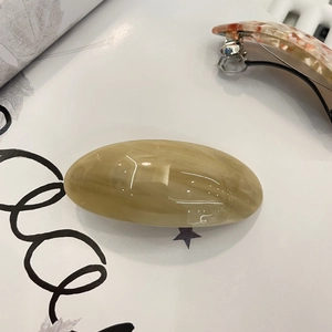 Detail of acetate oval spring hair clip with milk tea marble texture and metal clasp