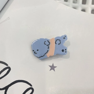 Détail d'une pince à cheveux petit chien bleu clair en acétate brillant avec pattes de chien