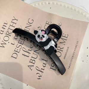 Pince à cheveux panda noir mat avec petite fleur rose sur un fond décoratif rose
