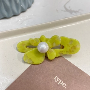 Detail of acetate flower hair clip with large faux pearl and marble finish texture