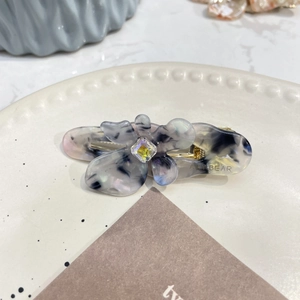 Dettaglio del fermaglio per capelli a fiore in acetato con cristallo e marmo
