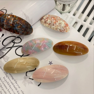 Detailed close-up of six premium oval acetate hair clips in assorted marble patterns