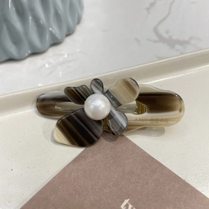 Macro detail of acetate flower hair clip with marble texture and pearl center