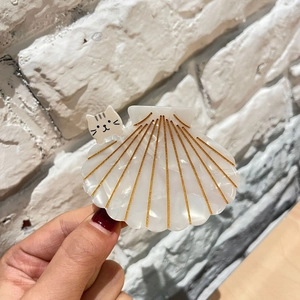 Détail d'une pince à cheveux en acétate en forme de coquillage avec motif chat