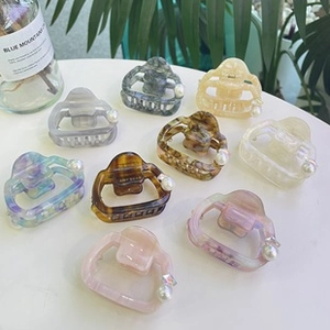 Flat lay of acetate flower hair claws with pearl and rhinestone details in diverse colors