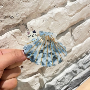 Détail de la pince à cheveux en acétate, forme de coquillage bleu marbré avec chaton
