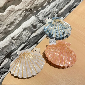 Détail de pinces à cheveux en acétate en forme de coquillage avec motif de chat