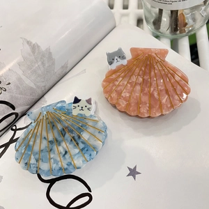 Détail de pinces à cheveux en acétate en forme de coquille avec accents de chat