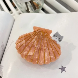 Pince à cheveux coquillage en acétate rose avec détail chat sur magazine