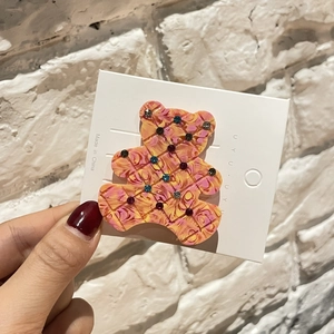 Détail d'une pince à cheveux ours en acétate avec strass colorés et texture à carreaux