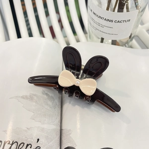 Pince à cheveux oreilles de lapin marron en acétate avec nœud crème et perle sur magazine