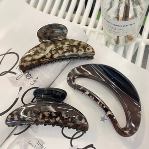 Three elegant tortoise shell hair claws in dark brown and beige on an art magazine