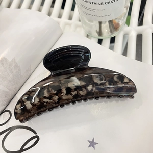 Elegant large marble patterned shark hair claw clip displayed on a minimalist magazine