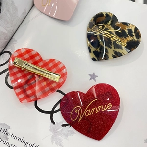 Dettaglio di fermagli per capelli a cuore con leopardo, glitter rossi e quadri