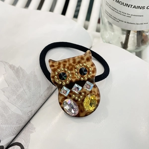 Detailaufnahme eines Eulen-Haargummis mit Leopardenmuster und bunten Kristallen
