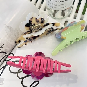 Tre fermacelli per capelli in acetato con motivi floreali e colori vivaci su sfondo bianco