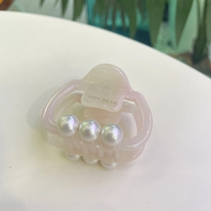 Detailed macro view of a light pink acetate hair claw clip decorated with glossy white pearls