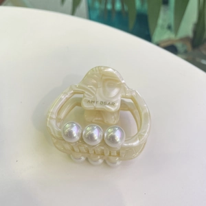 Detailed macro view of cream marble acetate hair claw clip with glossy white pearls