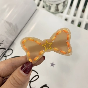 Detail of a handmade fuzzy star hair clip with orange knit trim and golden star charm