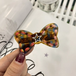 Detail of star bow hair clip with tortoiseshell finish and colorful woven edges
