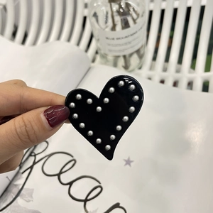 Détail de la pince à cheveux noire en forme de cœur avec perles blanches de style Y2K