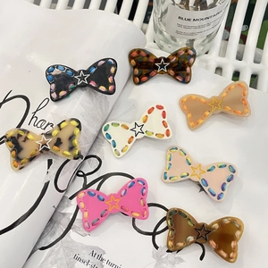 Close-up of handmade bow hair clips with metallic stars and colorful woven edges