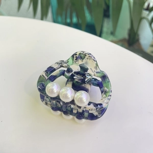 Detail view of acetate hair claw with green marble texture and three white pearls