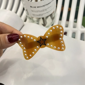Detail of amber acetate bow hair clip with white pearls and a star pattern design
