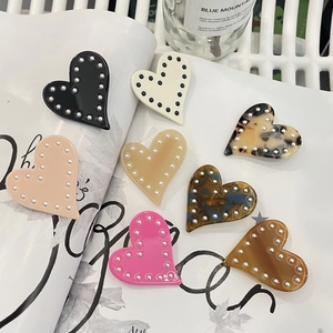 Détail de pinces à cheveux en forme de cœur avec perles et finitions en acétate coloré