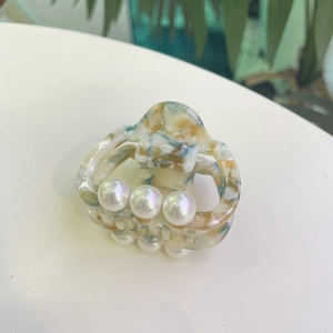 Macro shot of marble texture acetate hair claw with three elegant white pearls