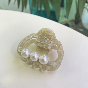 Detailed macro view of acetate hair claw with marble pattern and three white pearls