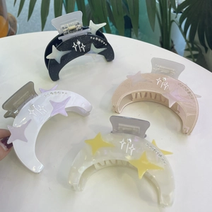 Dettaglio di quattro mollette a luna con strass e ciondoli a stella in vari colori