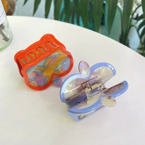 Detail of apple-shaped acetate hair claws with iridescent marble and pearlescent textures