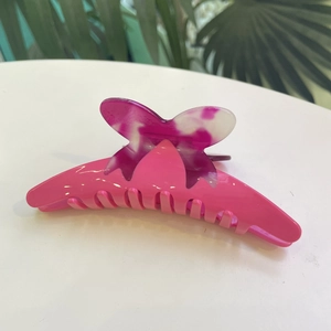 Detail of a bright pink butterfly hair claw clip with pearlescent resin finish