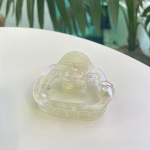 Vue détaillée de la pince à cheveux nacrée en acétate avec perle blanche et strass étincelant