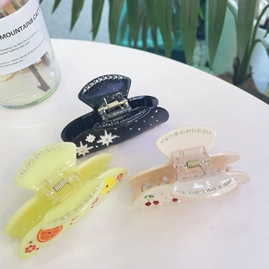 Detail view of acetate hair claws featuring lemon, cherry, and star rhinestone embellishments